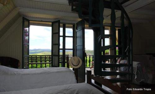 a bedroom with two beds and a balcony with a view at Capricho Asturiano in Santo Antônio do Leite