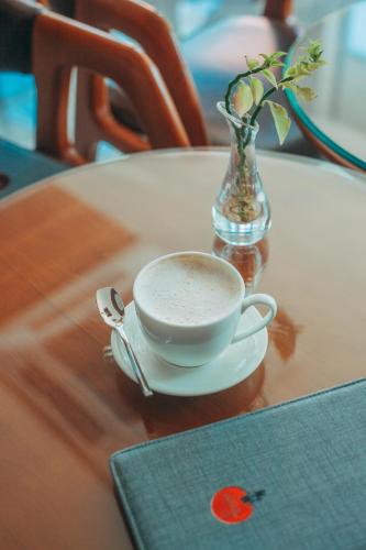 a cup of coffee on a table with a vase at Paralian Hulhumale' in Hulhumale