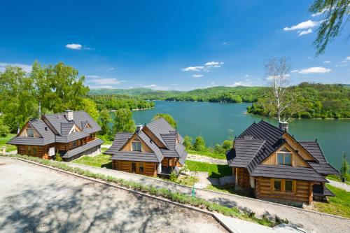 an aerial view of three log homes on a lake at Ostoja Spokoju in Olchowiec