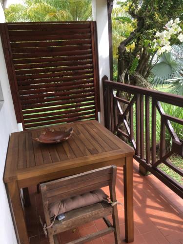 a wooden bench on a porch with a table at Le bungalow des bougainvilliers in Ducos