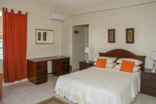a bedroom with a bed and a desk with orange pillows at Castles In Paradise Villa Resort in Vieux Fort