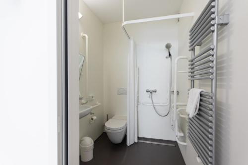 a white bathroom with a toilet and a shower at Chromotel self check-in in Mezzovico