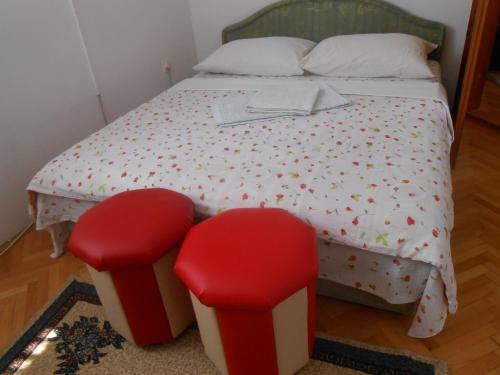 a bedroom with a bed with two red stools at Apartments & Hostel Zdrava Hrana in Mostar