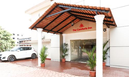 门格洛尔Treebo Comforts Inn, University Road Deralakatte的一辆白色汽车停在一栋建筑物前