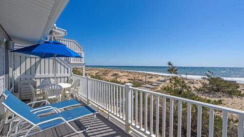 a balcony with chairs and an umbrella and the beach at Sea Crest in Amagansett