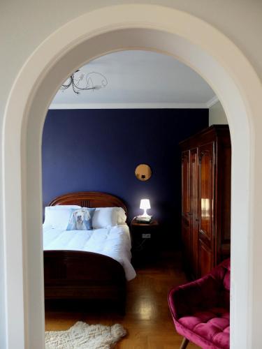 une chambre avec un lit avec un mur bleu dans l'établissement Chez Thomas, à Colmar