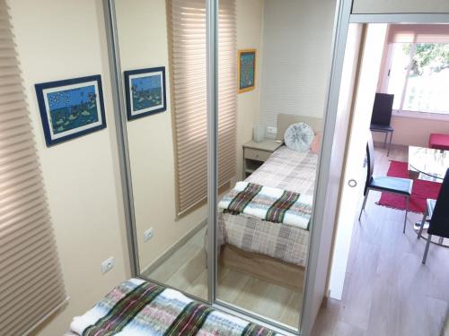 Una pequeña habitación con una cama y un espejo. en Cosy Well Located Apartment with swimming pool Tenerife, en Tacoronte