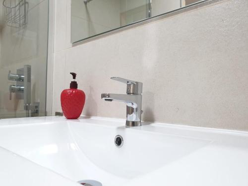 ein Waschbecken mit einer roten Vase darauf in der Unterkunft Cosy Well Located Apartment with swimming pool Tenerife in Tacoronte