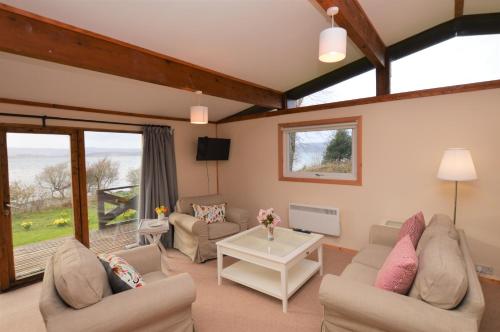 sala de estar con sofás y mesa en Clamshell Lodge, en Otter Ferry