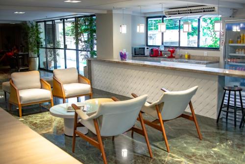 a bar with white chairs and a counter at Rede Andrade Casa Blanca in Fortaleza