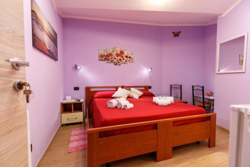 um quarto com uma cama vermelha e paredes roxas em Rio Launaxi Guest House em Teulada