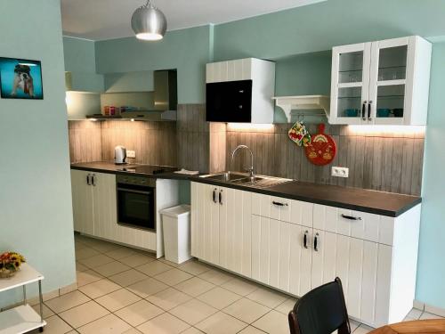 - une cuisine avec des placards blancs et un évier dans l'établissement Renovated Apartment in Antwerp city center, à Anvers