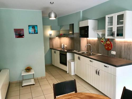 a kitchen with white cabinets and a sink and a table at Renovated Apartment in Antwerp city center in Antwerp