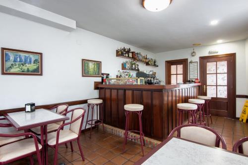 een restaurant met een bar met rode stoelen en tafels bij Hotel Salldemar in Santillana del Mar