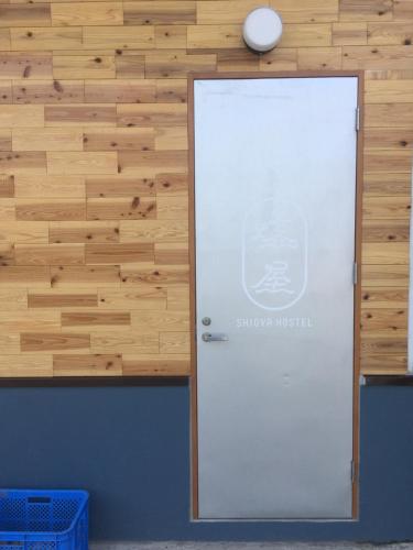 a white door with a sign on a wooden wall at Shioya Hostel in Akune