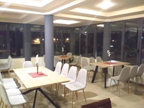 a dining room with tables and chairs and windows at River Side Rooms in Elassona
