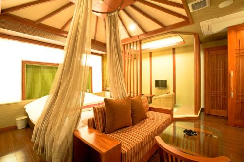 a bedroom with a bed and a couch in a room at Hotel Bintang Pari Resort (Adult Only) in Kobe