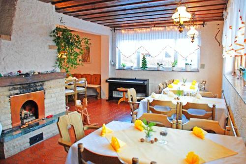 a restaurant with tables and chairs and a fireplace at Pension "Bayerwald" in Frauenau