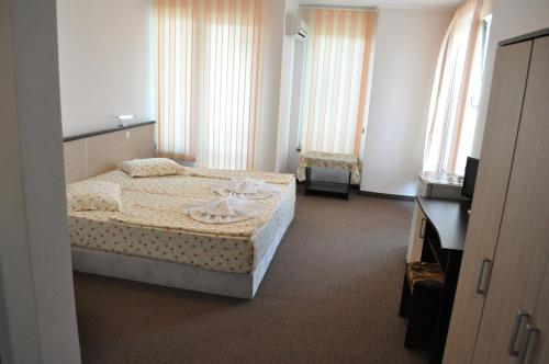 a bedroom with a bed and a tv and windows at St. George Apartments in Nesebar