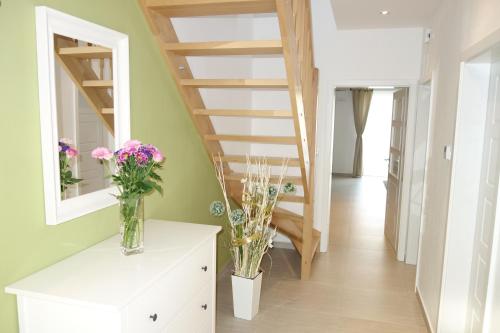 a room with a staircase and vases of flowers on a dresser at Lednicko-valtický apartmán in Hlohovec