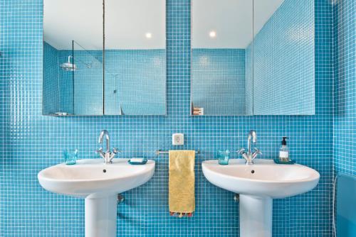 een blauw betegelde badkamer met 2 wastafels en spiegels bij Cubo in Sintra