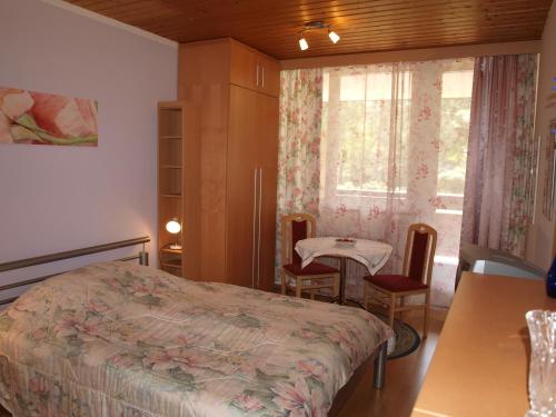 a bedroom with a bed and a table and a window at Kurpark Appartements in Bad Hofgastein