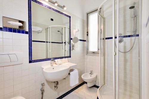 een witte badkamer met een wastafel en een douche bij Hotel San Giusto in Trieste