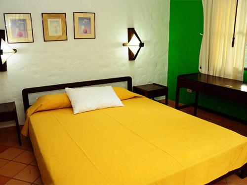 a bedroom with a yellow bed and a desk at Finca El Jecho in Villavicencio