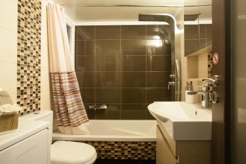 a bathroom with a toilet and a tub and a sink at Pretty rooms in Gold and Blue apartment in safe central area in Athens