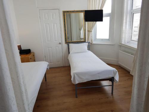 a room with two beds and a mirror and a window at Boscombe Reef Hotel in Bournemouth