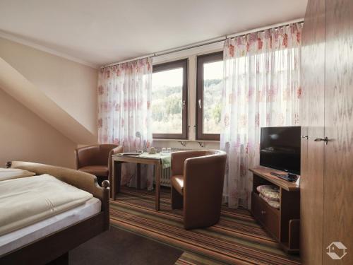 a hotel room with a bed and a table and a television at Café-Pension Endehof in Oberprechtal