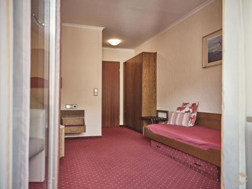 a hotel room with a bed and red carpet at Café-Pension Endehof in Oberprechtal