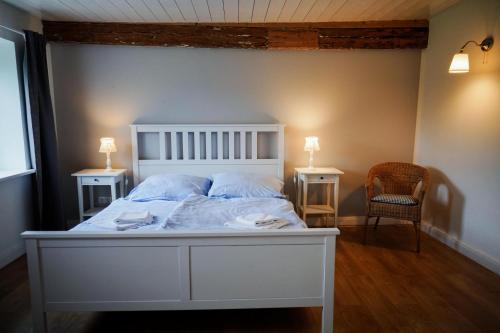 a bedroom with a white bed with two tables and a chair at Landhaus Habernis in Steinberg