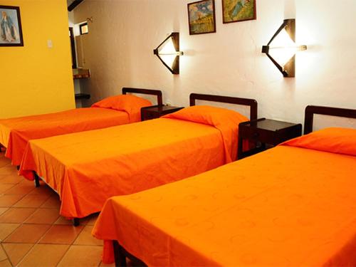 three beds in a room with orange sheets at Finca El Jecho in Villavicencio