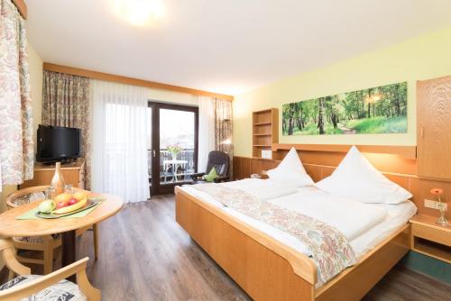 Habitación de hotel con cama y mesa en Hotel Garni Vier Jahreszeiten en Bad Füssing