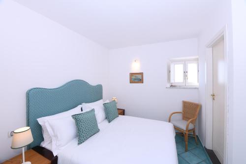 een wit bed met een blauw hoofdeinde in een slaapkamer bij Amalfitano Apartments in Amalfi
