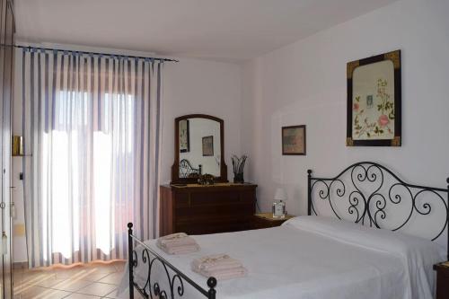 una camera con letto bianco e specchio di La casa del viaggiatore a Codrongianos