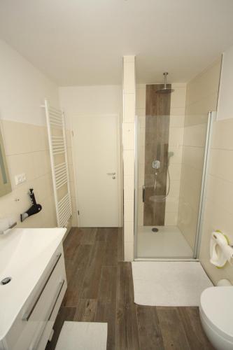 a white bathroom with a shower and a toilet at Familienfreundliches Ferienhaus in Kröpelin in Kröpelin