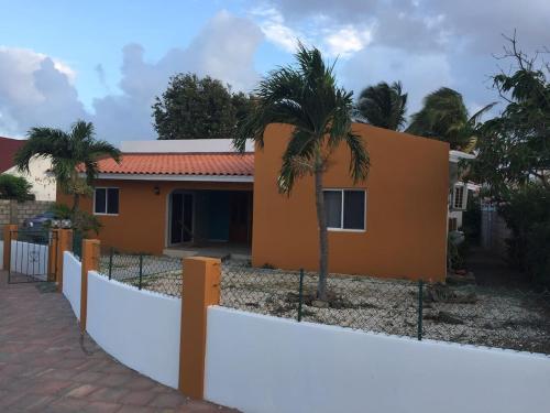 una casa con una valla y palmeras en Luna 39, en Oranjestad