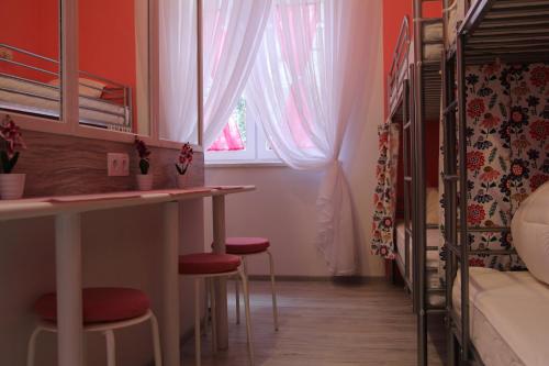 a small room with a bed and a table and stools at Lorf Hostel&Coffee in Kraków