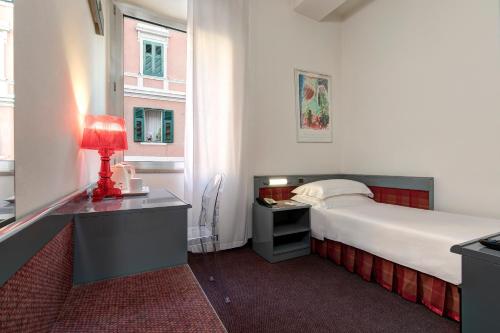 a bedroom with a bed and a desk with a lamp at Hotel San Giusto in Trieste