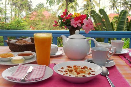 a table with breakfast food and a pitcher of orange juice at Villa Jacaranda in Varkala