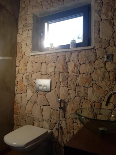 bagno in pietra con servizi igienici e finestra di The Fabris - Country Villa a Lumbarda (Lombarda)
