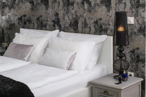 uma cama branca com almofadas brancas e um candeeiro sobre uma mesa em Note Luxury Apartments em Zagreb