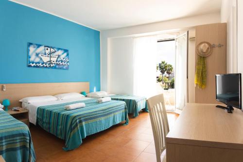 a hotel room with two beds and a television at Hotel Baia Del Sole in Marina di Ragusa