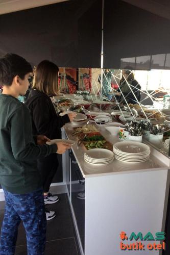 a group of people standing at a buffet with food at Mas Butik Otel in Edremit