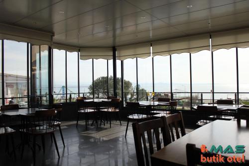 a restaurant with tables and chairs and windows at Mas Butik Otel in Edremit