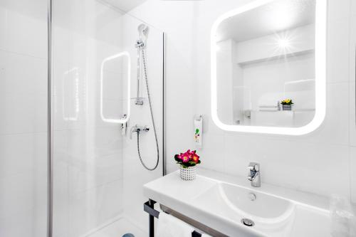 y baño blanco con lavabo y ducha. en ibis Styles Perpignan Canet En Roussillon en Canet-en-Roussillon