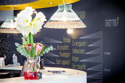 a vase of flowers on a table with two lights at ibis Styles Perpignan Canet En Roussillon in Canet-en-Roussillon