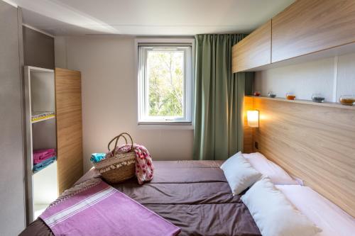 a bedroom with a bed and a window at Camping Paris-Est in Champigny-sur-Marne
